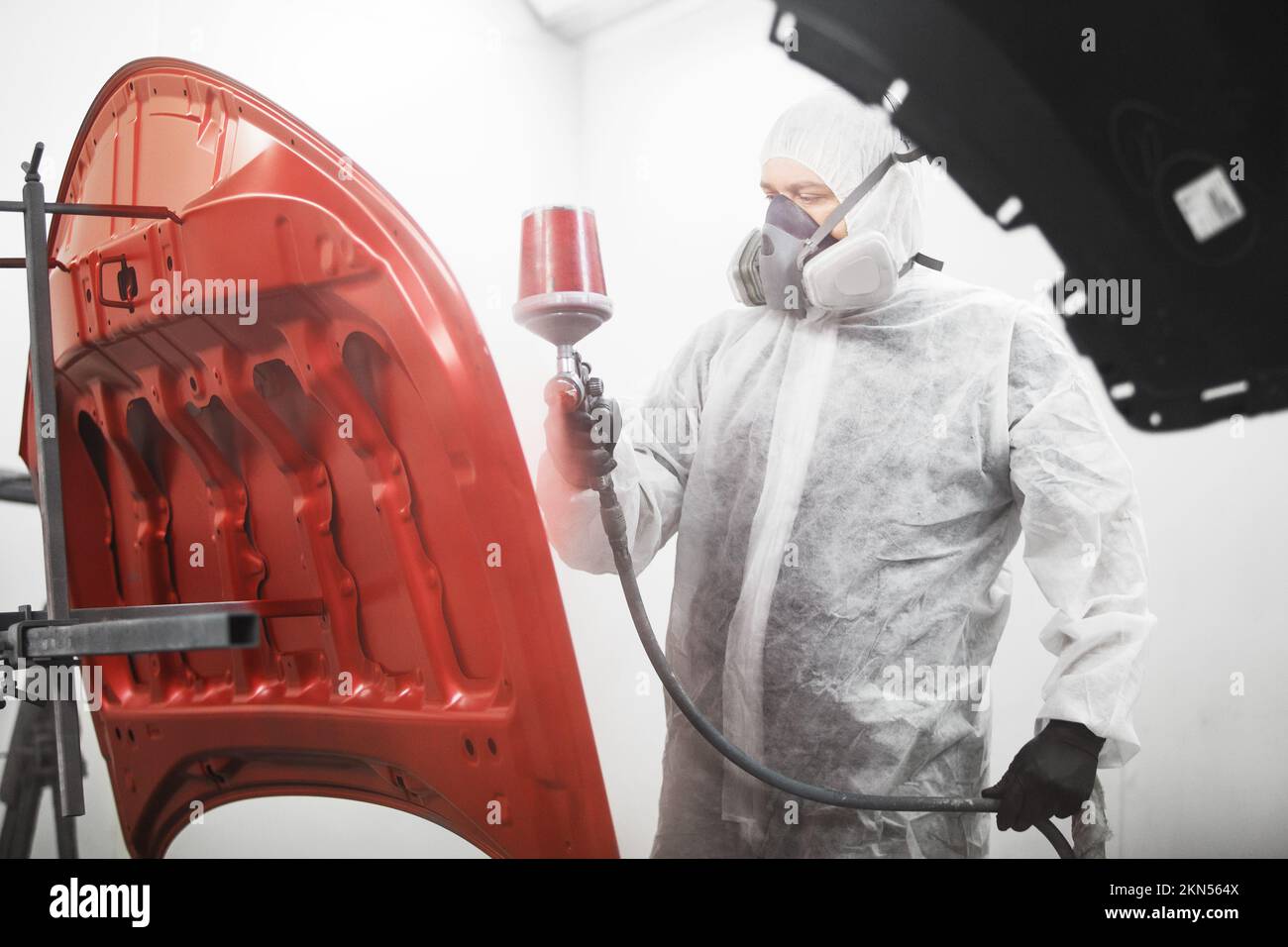 Verniciatura carrozziere in maschera e indumenti protettivi verniciatura cappa in camera di verniciatura. Foto Stock