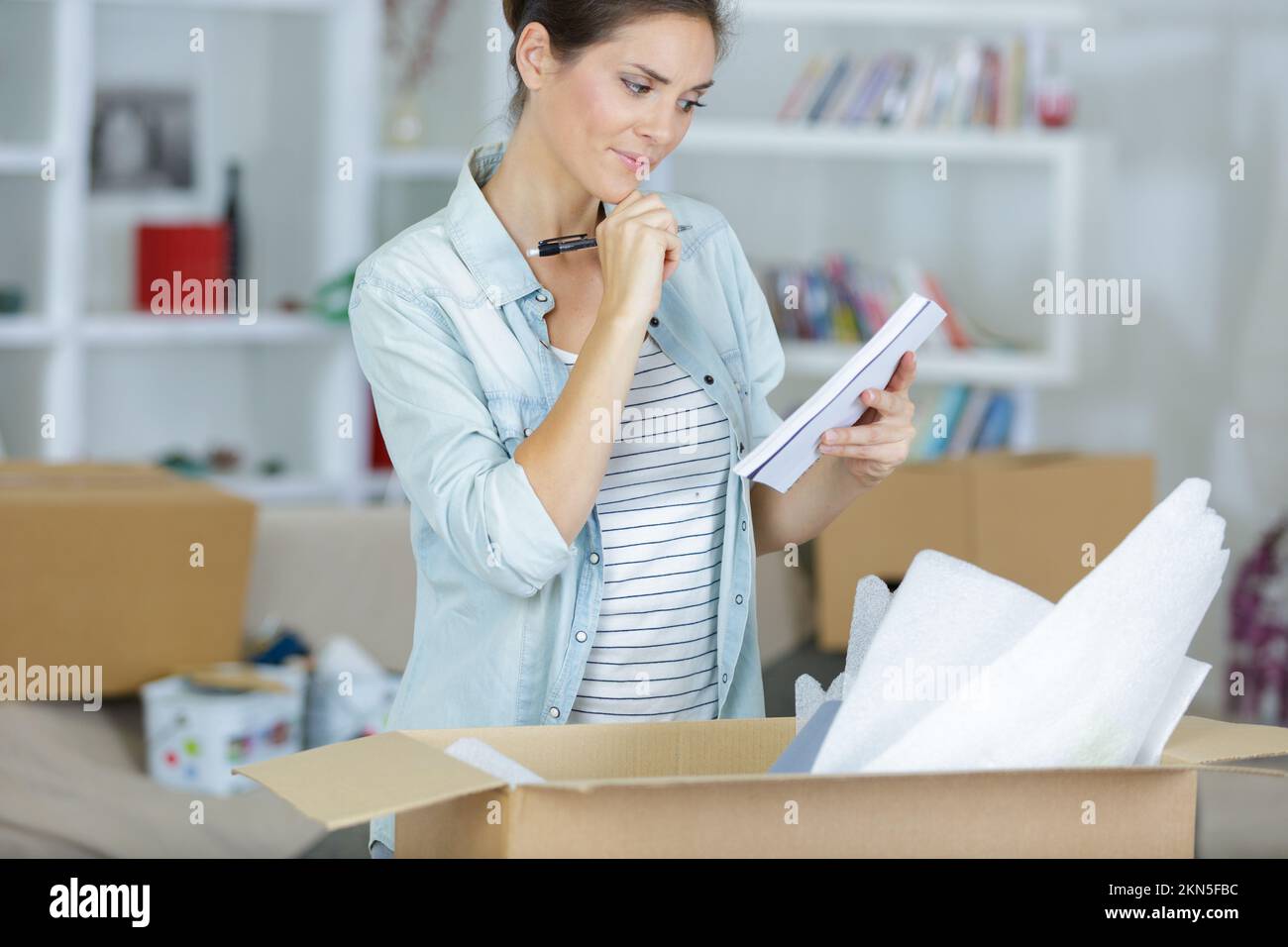 donna che guarda la lista di imballaggio Foto Stock