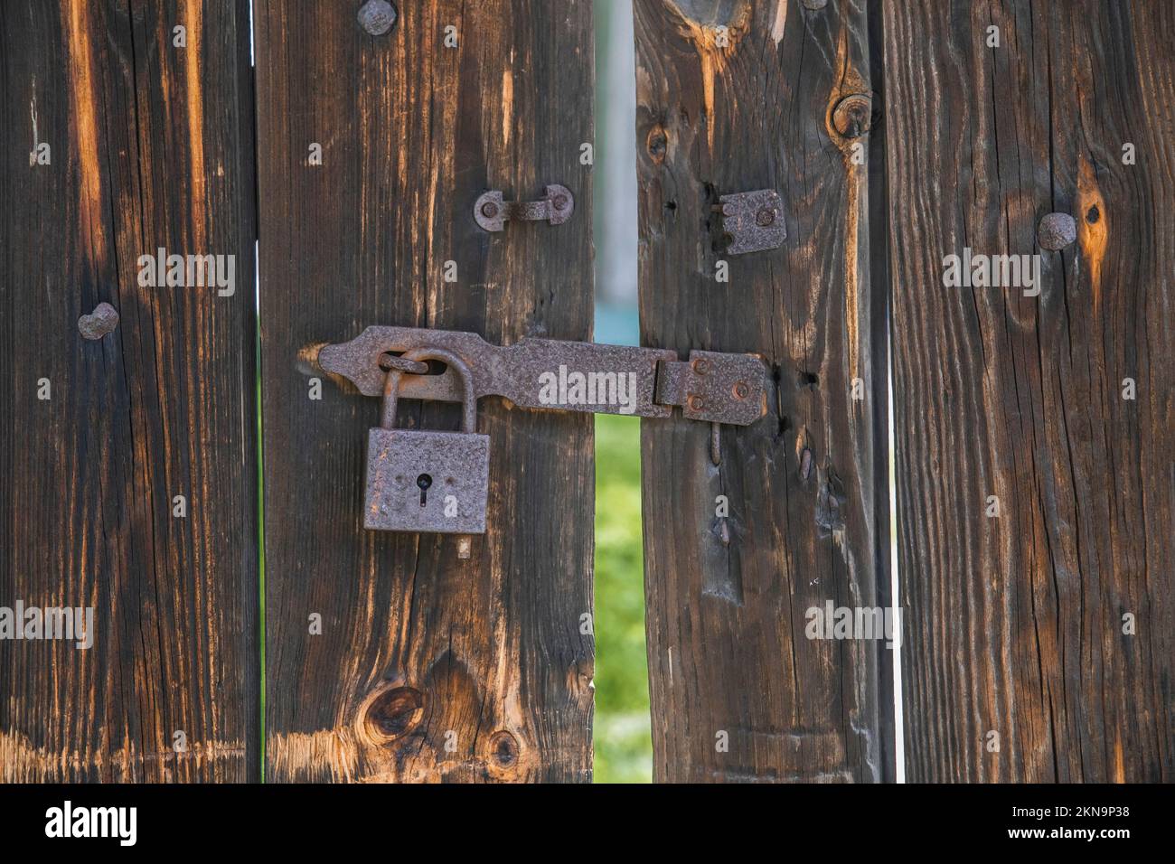vecchio cancello di legno con lucchetto arrugginito. Sfondo Foto Stock