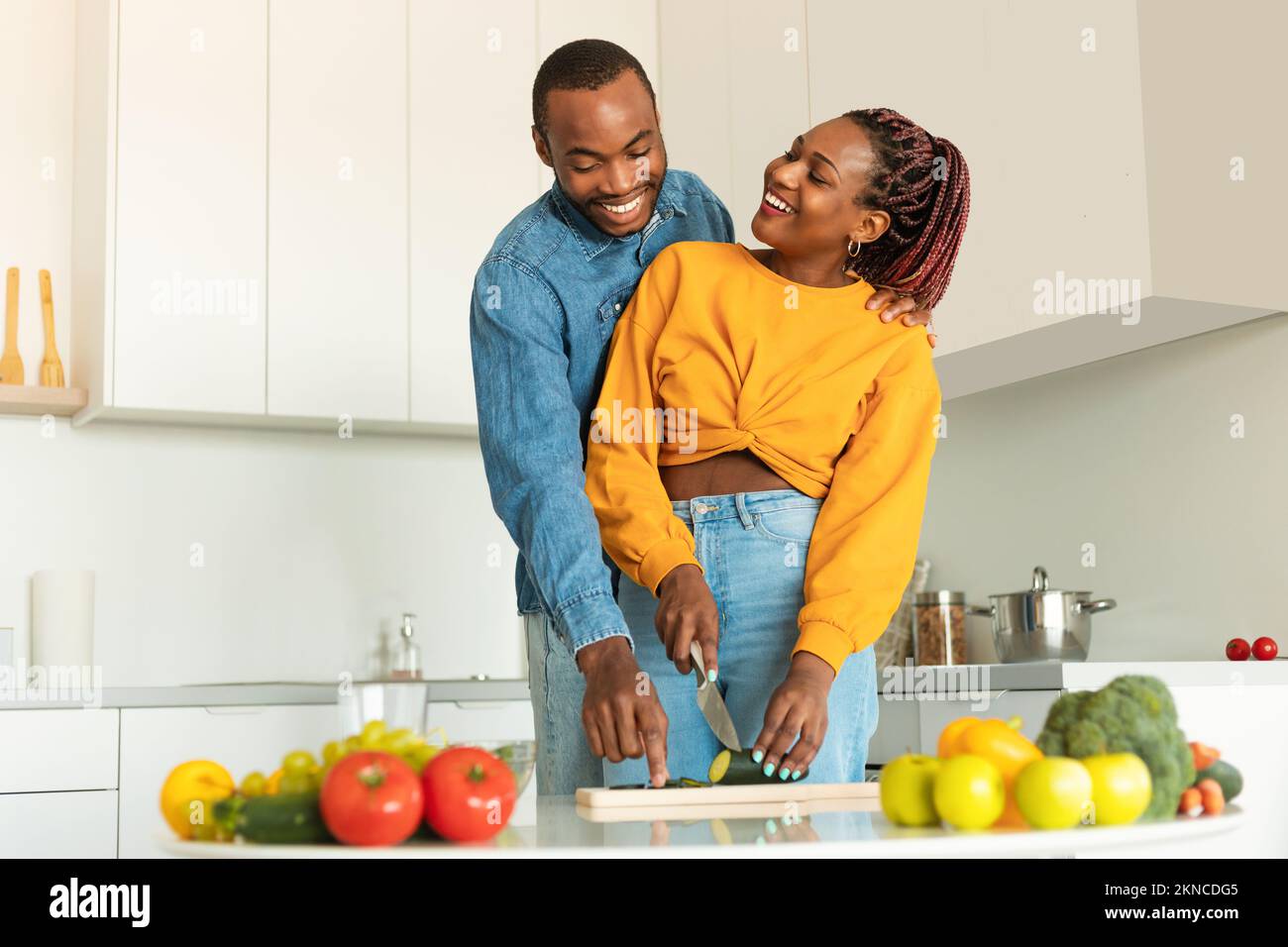 Romantici sposi neri che cucinano un pranzo sano a casa, felice uomo e donna che si gustano insieme gustosi piatti Foto Stock