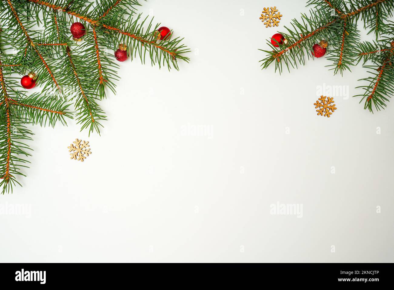 Composizione natalizia con rami di abete, palle rosse e fiocco di neve in legno su sfondo bianco. Piatto, spazio copia, vista dall'alto festive MOC Foto Stock