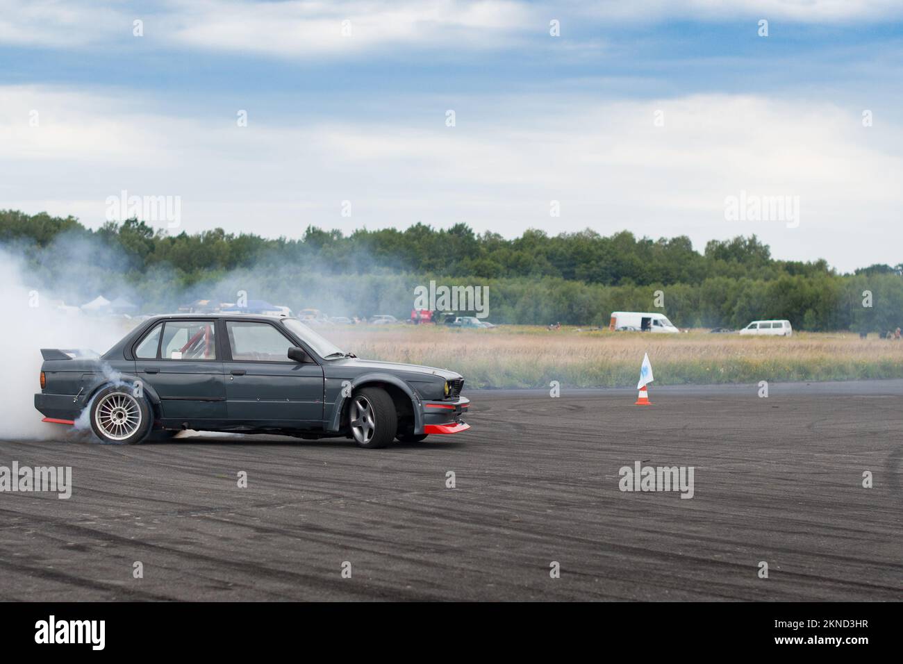 Auto da corsa che parte sulla pista di velocità, pilota professionista che guida l'auto sulla pista di gara con fumo, tessuto astratto e sfondo nero piste pneumatici scivolano su Foto Stock
