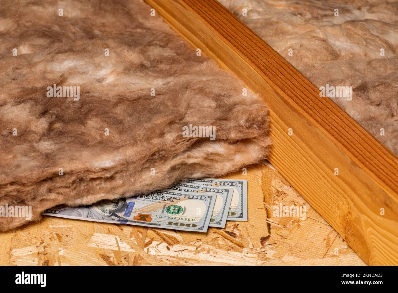 Isolamento in fibra di vetro in soffitta di casa con denaro contante. Risparmio energetico domestico, costi di riscaldamento e raffreddamento e concetto di costruzione. Foto Stock