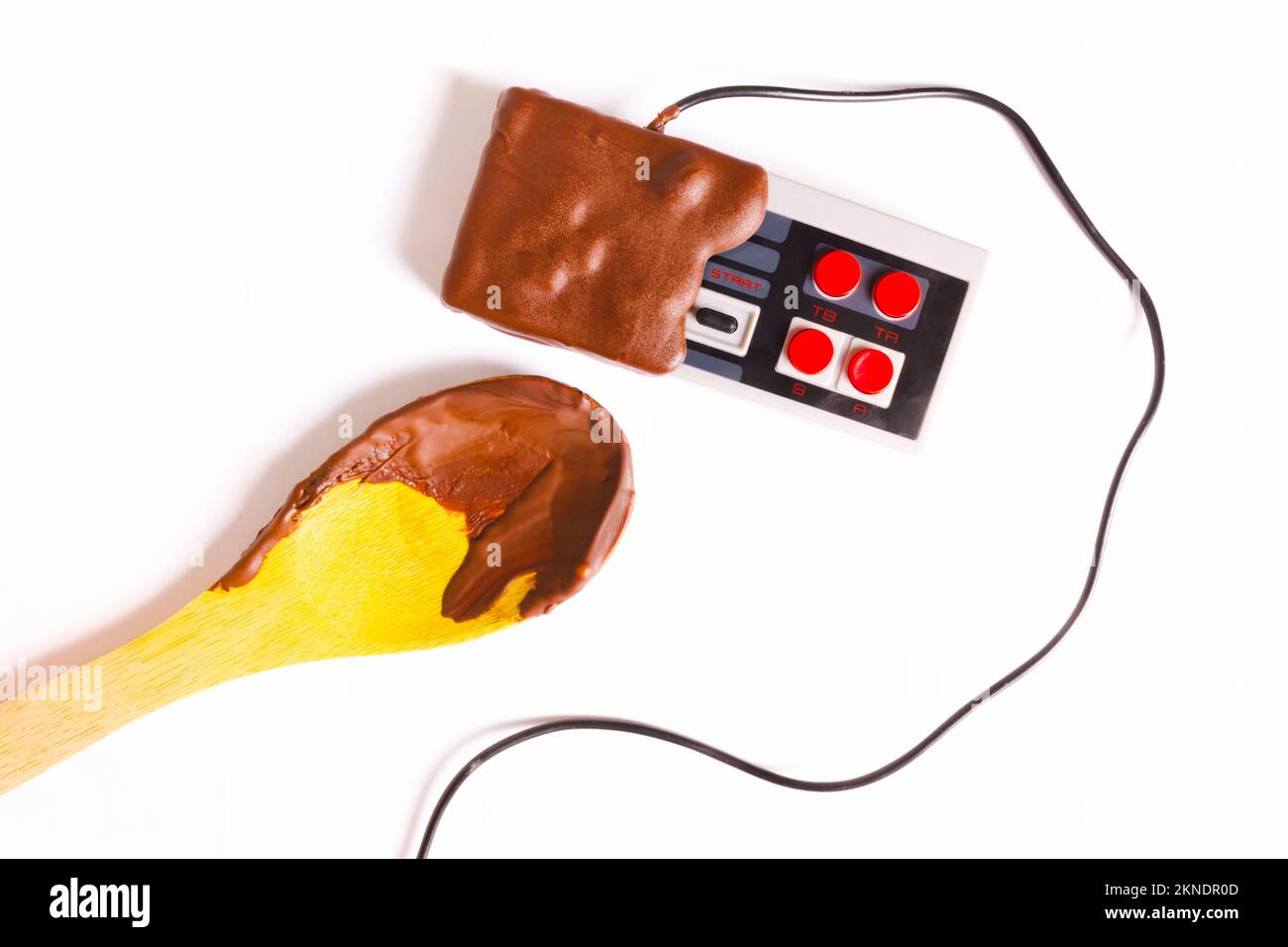 Gamification di delizie al cioccolato con il joystick di gioco rivestito di choc in retrò modernizzato. Fundue Foto Stock