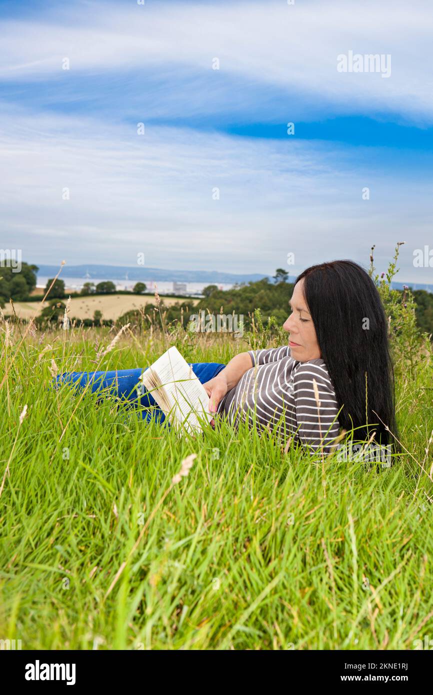 Donna sdraiata e rilassante in un campo erboso Foto Stock