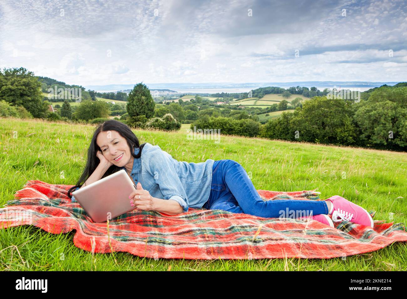 Donna sdraiata e rilassante in un campo erboso Foto Stock