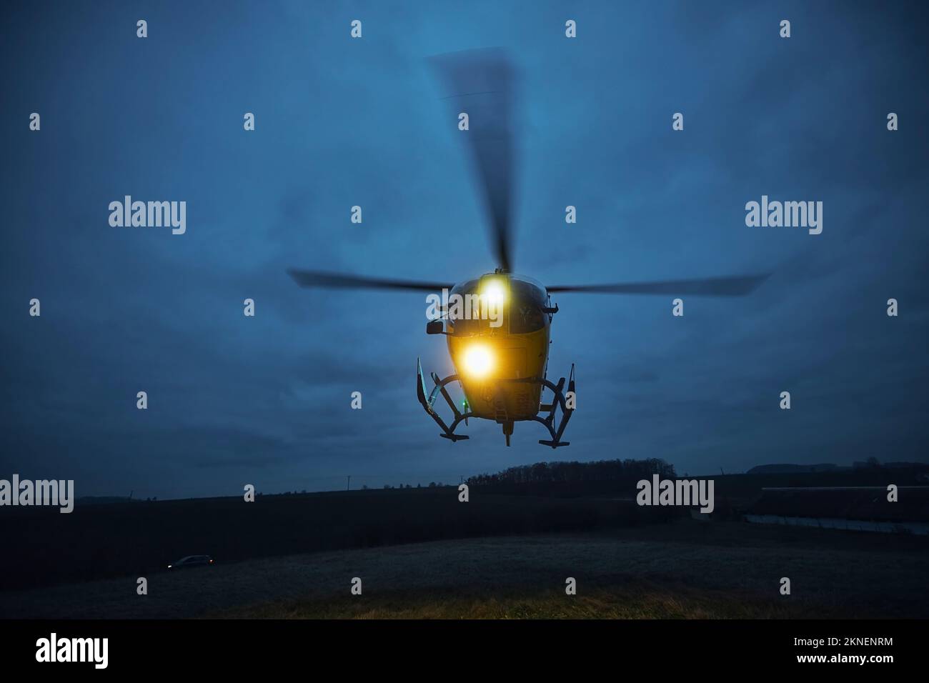 Elicottero volante di servizio medico di emergenza durante il decollo dal prato al crepuscolo. Temi di salvataggio, aiuto e speranza. Foto Stock