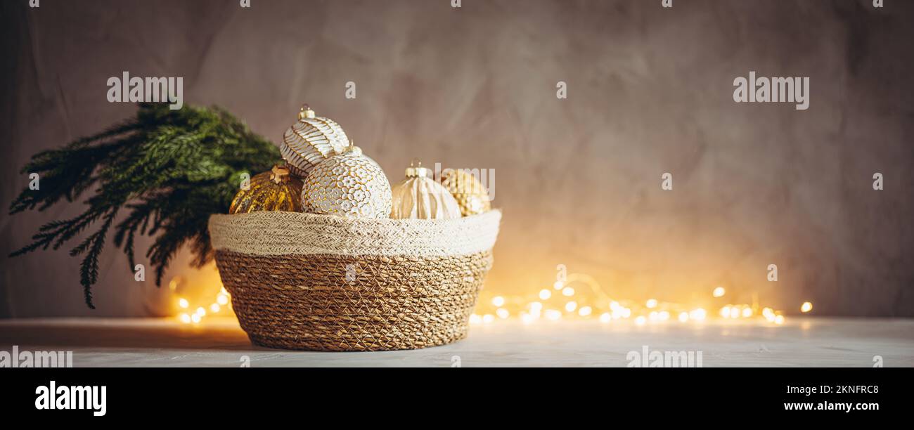 Ramo dell'albero di Natale e baubles in cesto intrecciato con luci bokeh di Natale sullo sfondo Foto Stock