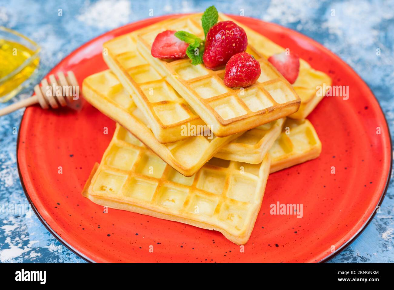 Dolce dessert waffle belgi con fragole e mirtilli su un piatto con miele Foto Stock