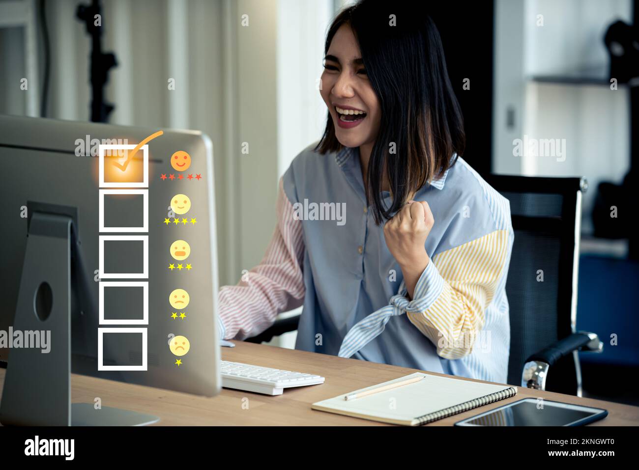 Giovane donna asiatica felice che utilizza il computer con servizio clienti e cinque stelle di soddisfazione. Foto Stock