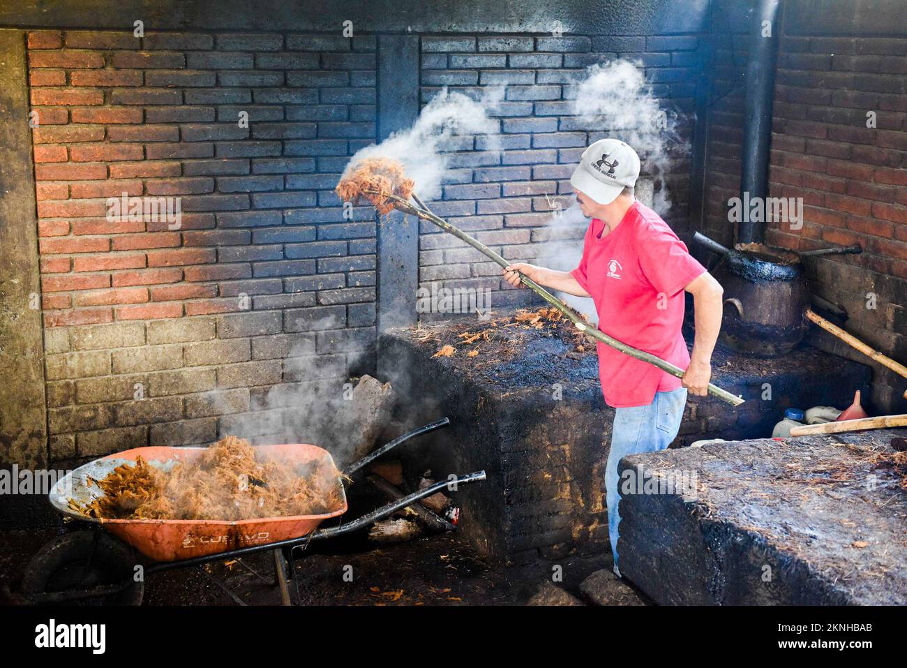 Dopo il primo processo di distillazione dei cuori di agave schiacciati, la purea calda viene rimossa manualmente , distilleria artigianale Mezcal , Oaxaca Mexico Foto Stock