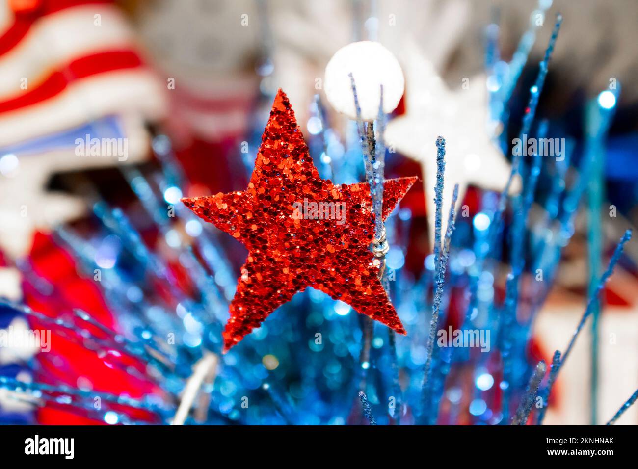 Festivo sfondo di festa con bandiera sfocata in background e glitter elementi a stella e bokeh decorativi in primo piano - rosso bianco e blu Foto Stock