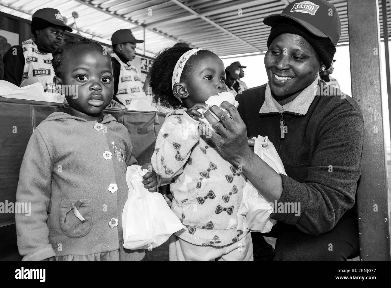 Una vista dei bambini africani che mangiano panini nel parco giochi di un asilo in scala di grigi Foto Stock