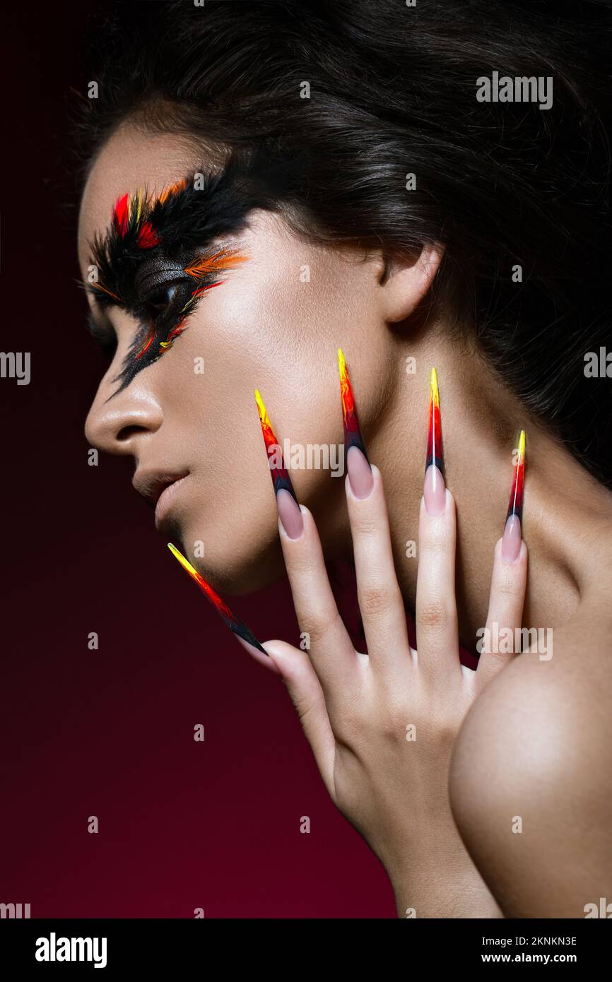 Bella ragazza a immagine dell'uccello Phoenix con trucco creativo e unghie lunghe. Design manicure. La bellezza del viso. Foto scattate in studio Foto Stock