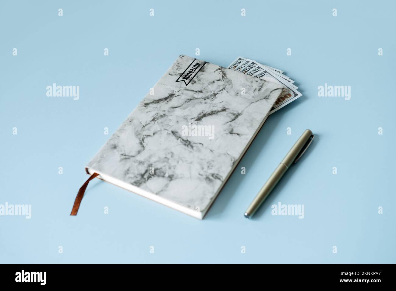 Aumento del costo della vita, inflazione, finanziaria, concetto di crisi economica. Notebook con banconote in denaro contante su sfondo blu. Foto Stock