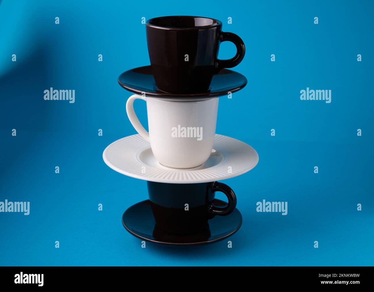 tazze da caffè fotografiche su piattini su sfondo blu in posizione verticale Foto Stock