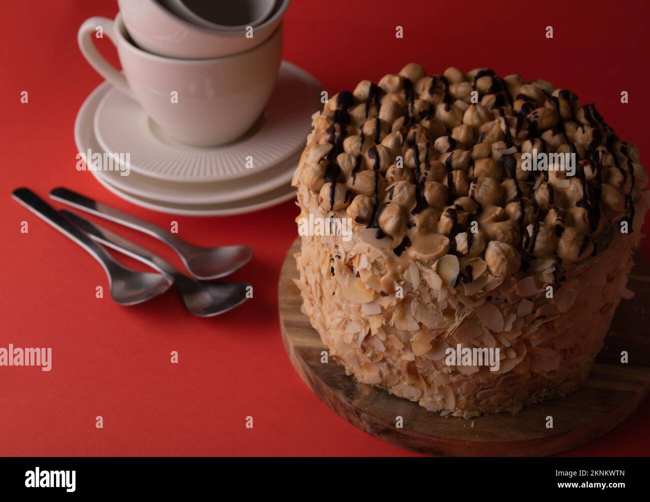 foto di una torta di noce su un asse di legno e piatti su sfondo rosso Foto Stock