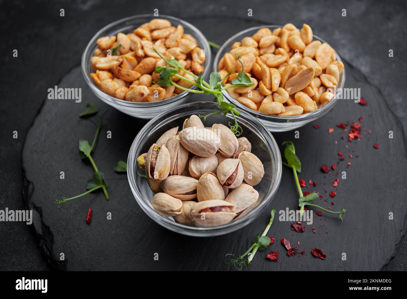 Noci salate, pistacchi e arachidi, per la birra, su fondo scuro Foto Stock