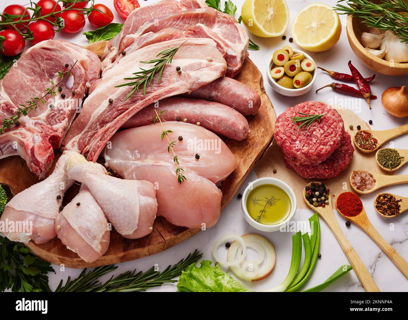 Carne fresca cibo sfondo. Carne di maiale, costolette, hamburger di bistecca di manzo, filetto di pollo e pepite con erbe, verdure e spezie isolate sul dorso bianco Foto Stock