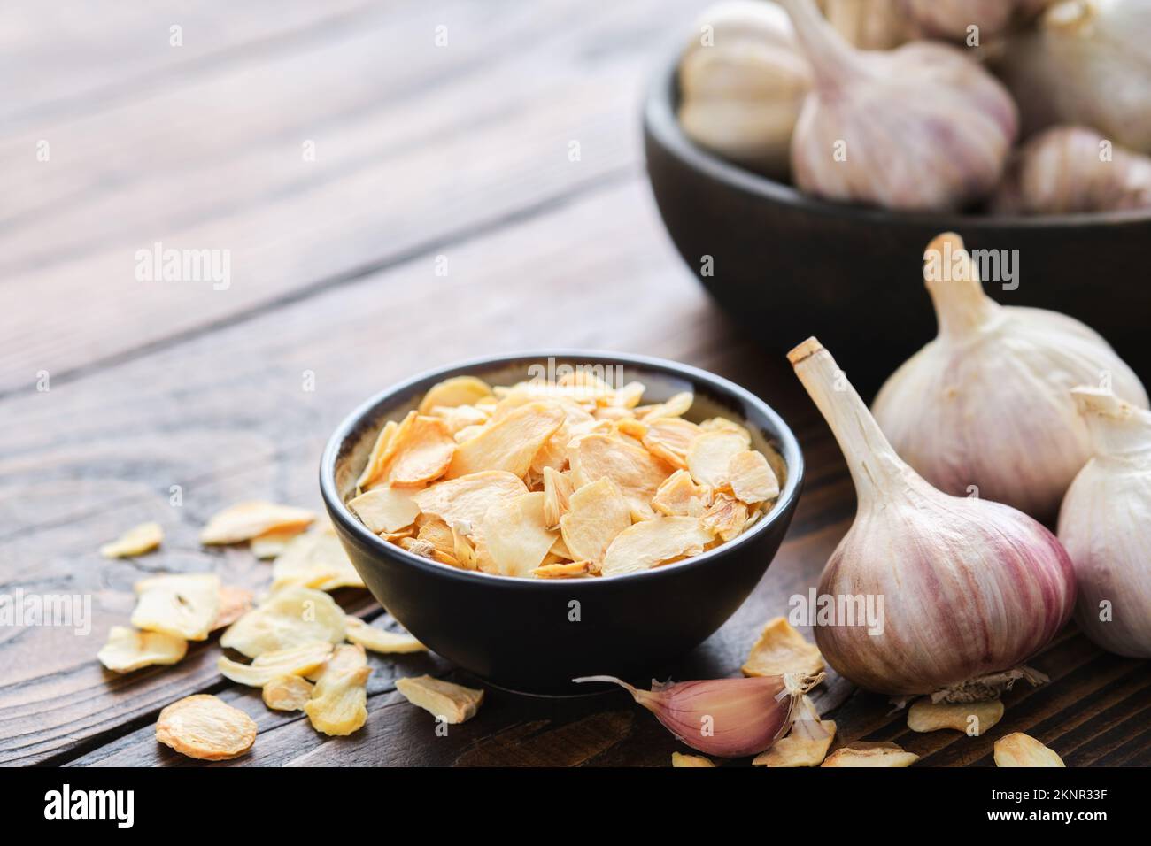 Ciotola di fiocchi d'aglio secchi. Spicchi d'aglio e teste. Foto Stock