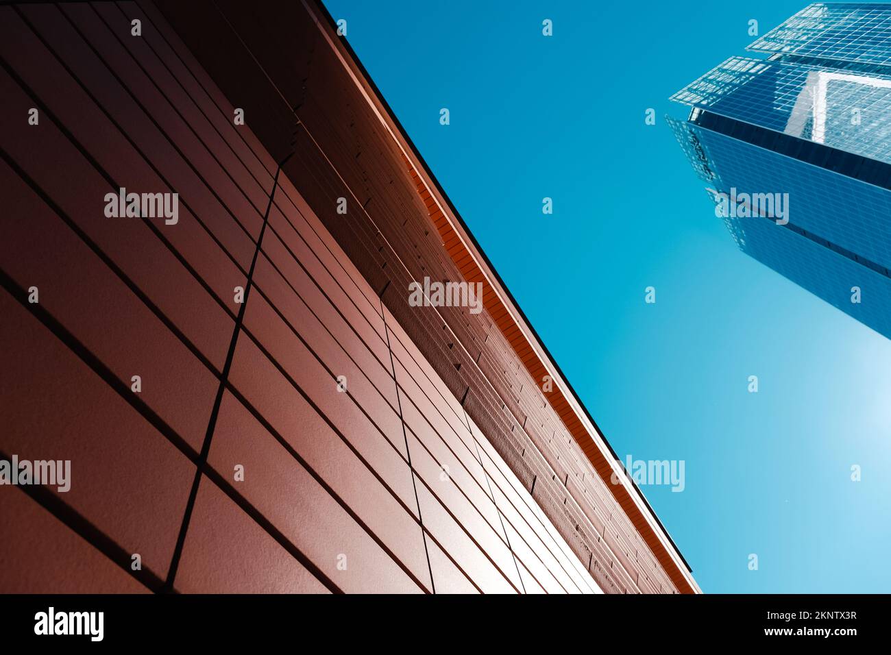 L'ombra forma un gradiente pulito sulle piastrelle rosse e sugli edifici alti con cielo chiaro. Foto Stock