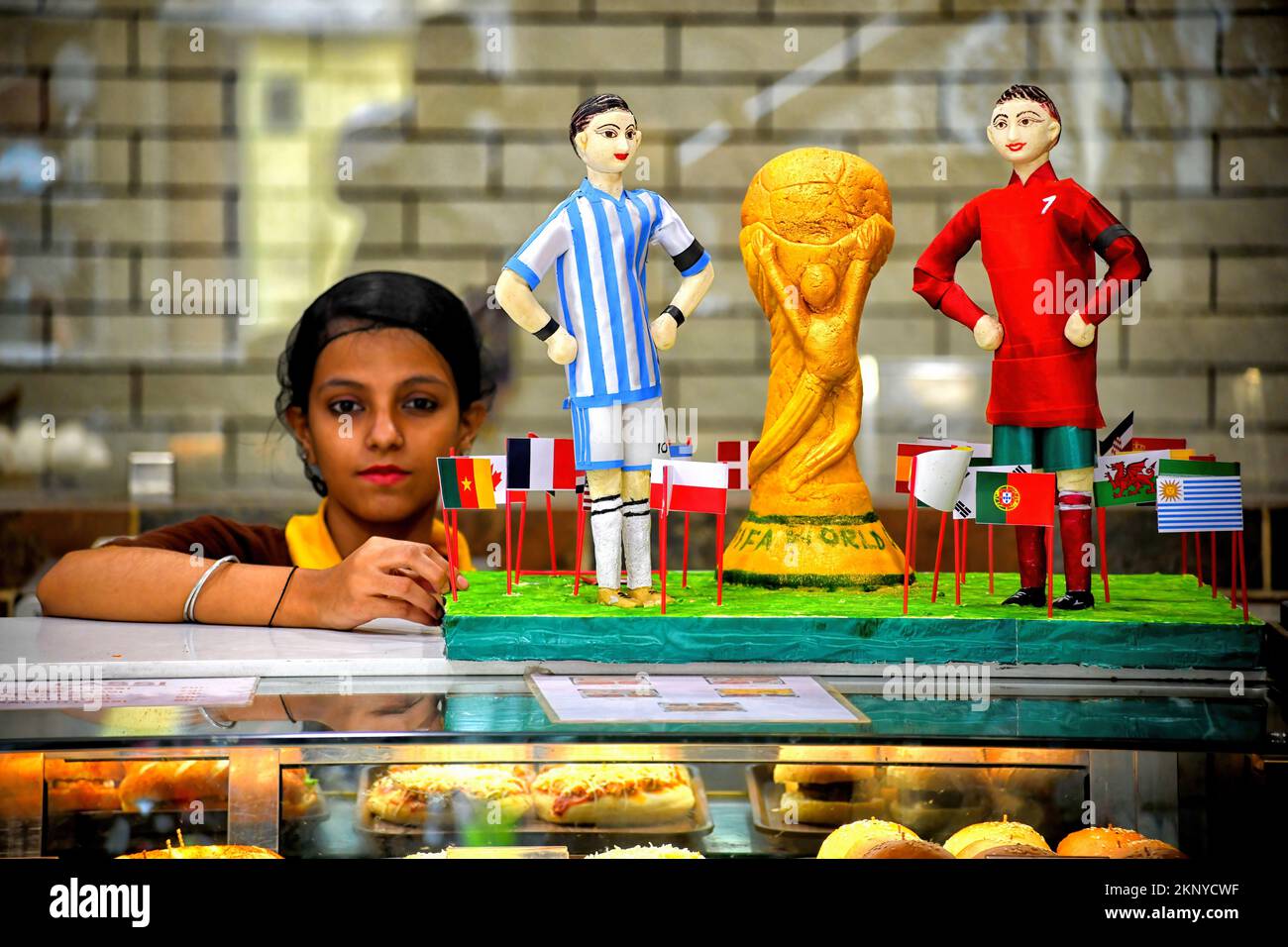 Kolkata, India. 26th Nov 2022. Un lavoratore fa una replica del trofeo della Coppa del mondo FIFA 2022 con i modelli Lionel messi e Cristiano Ronaldo realizzati con dolci in un negozio di dolciumi in vista della Coppa del mondo FIFA. (Foto di Avishek Das/SOPA Images/Sipa USA) Credit: Sipa USA/Alamy Live News Foto Stock