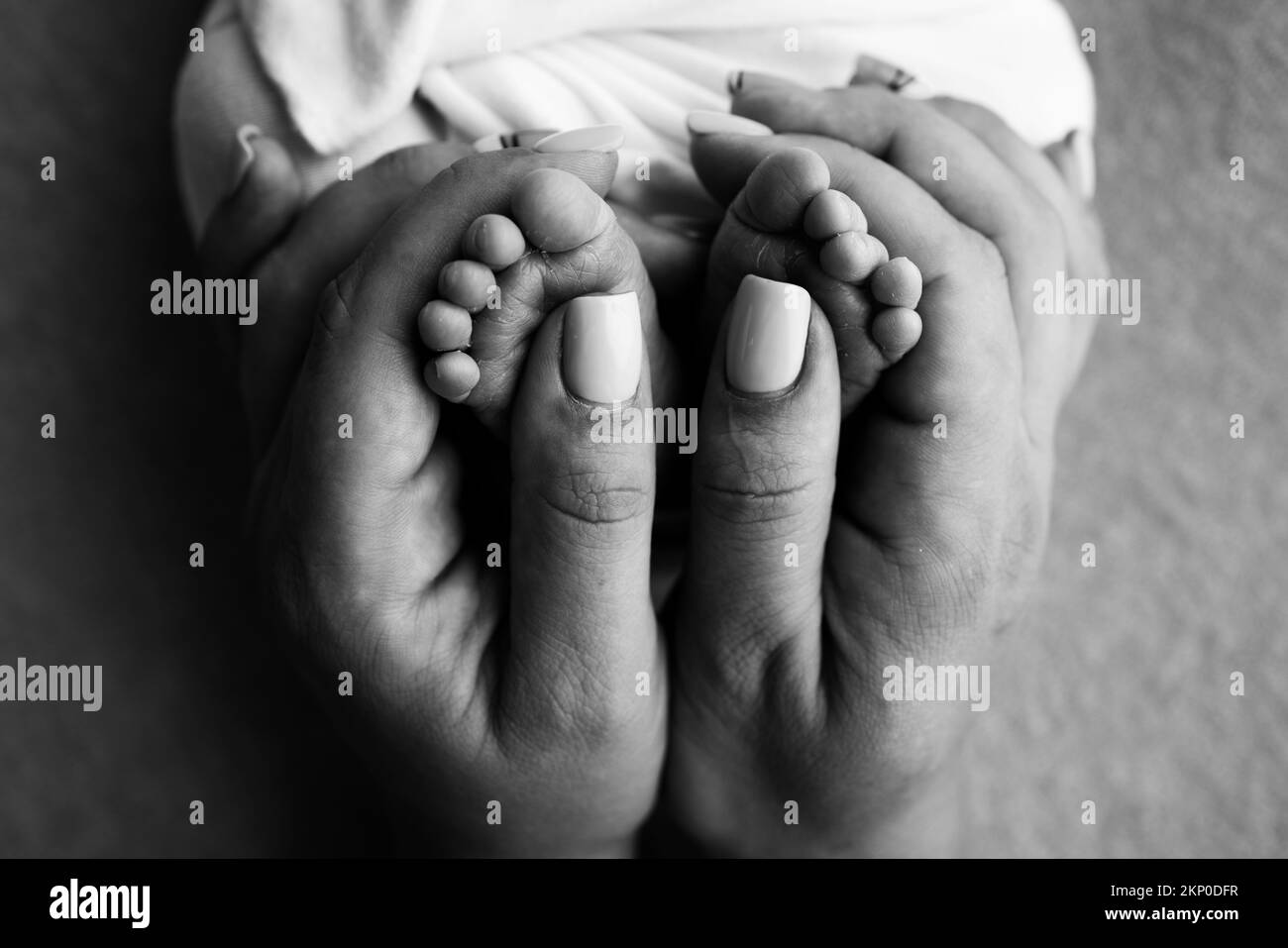 Gambe, dita dei piedi, piedi e talloni di un neonato.la madre tiene delicatamente le gambe del bambino. Foto Stock