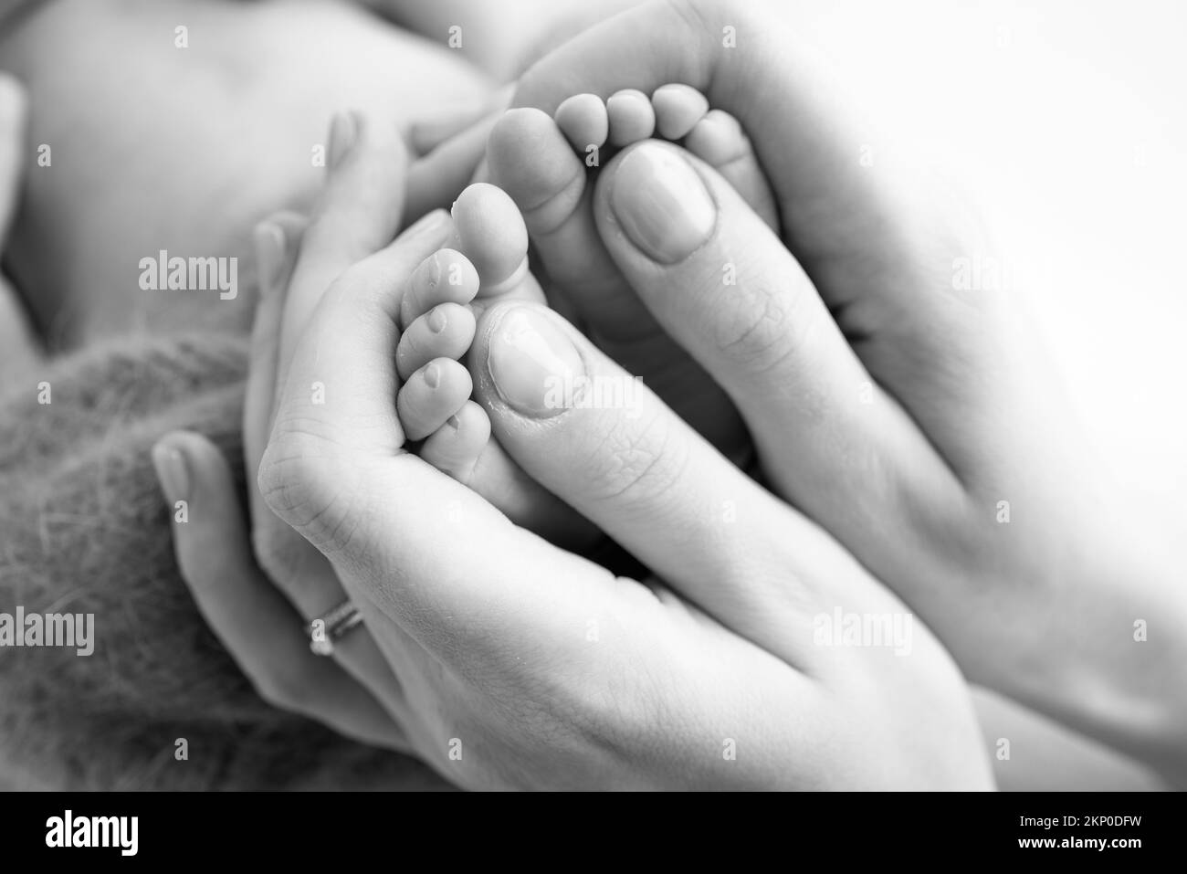 Gambe, dita dei piedi, piedi e talloni di un neonato. La madre tiene delicatamente le gambe del bambino. Foto Stock