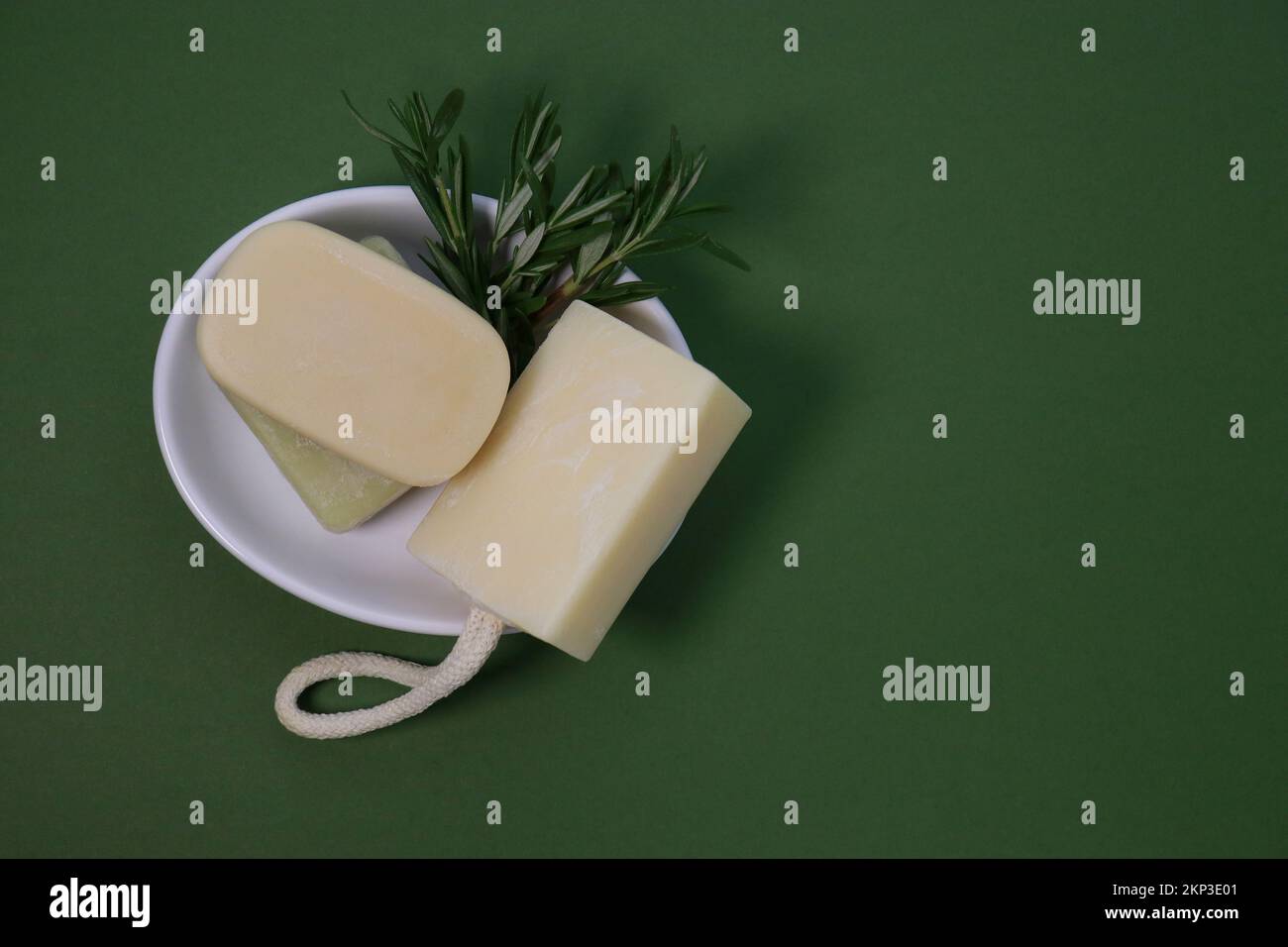 primo piano delle saponette fatte a mano su un vassoio per sapone bianco, fondo verde Foto Stock