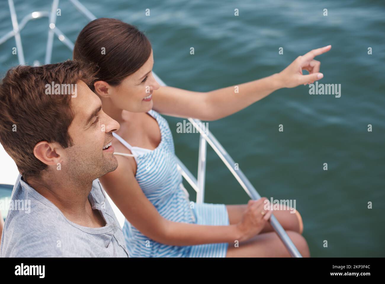 Guarda là. una giovane coppia attraente che si gode un giro in barca insieme. Foto Stock