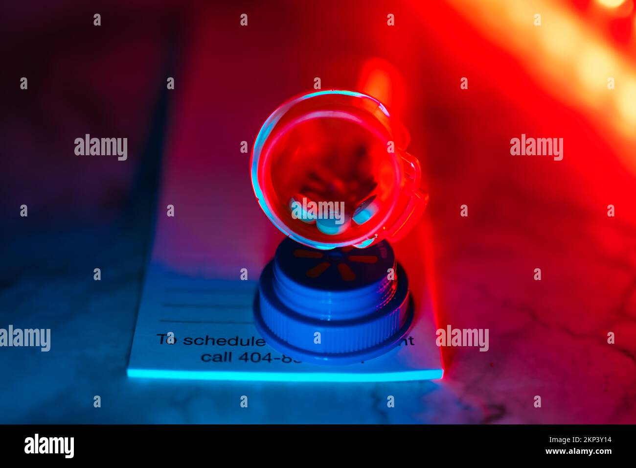 Aprire il flacone del medicinale con le pillole per qualcuno. sulla parte superiore di un tastierino di prescrizione luci a led al neon Foto Stock