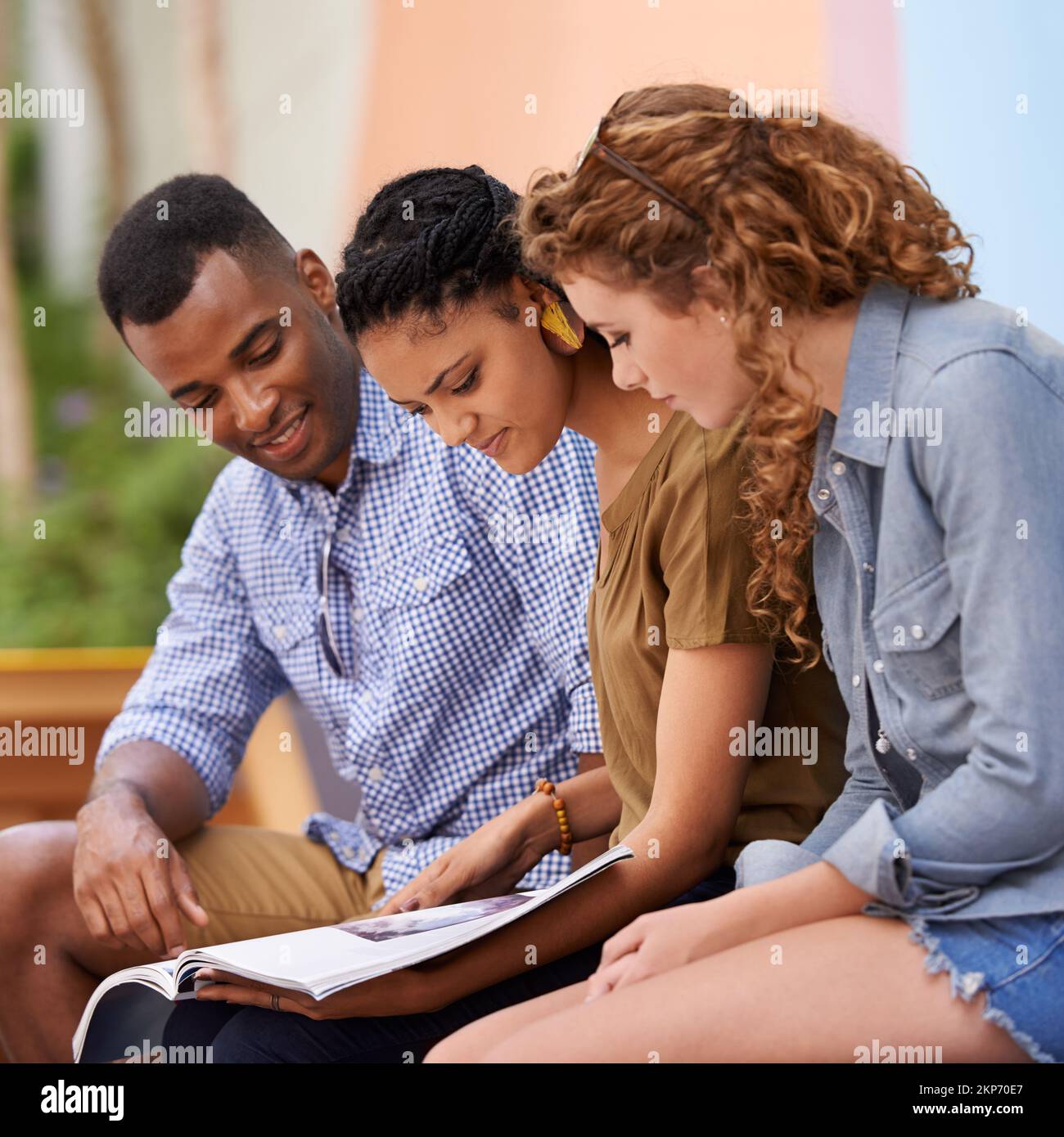 Fonti di ispirazione. Tre giovani studenti che leggono un libro all'aperto. Foto Stock