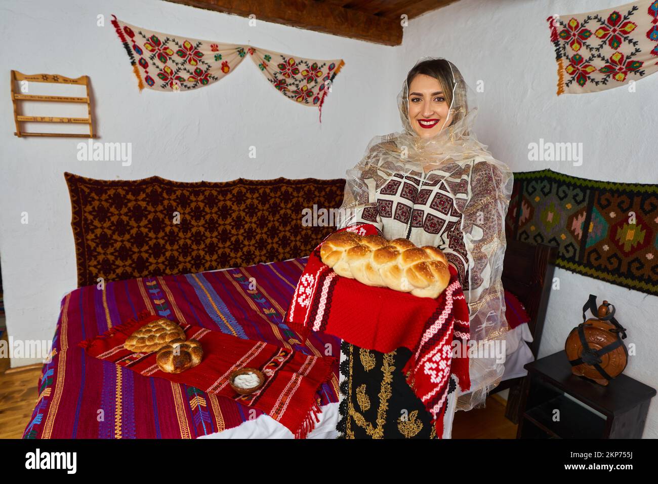Giovane donna rumena vestita in costume tradizionale popolare, in una casa rurale tradizionale Foto Stock