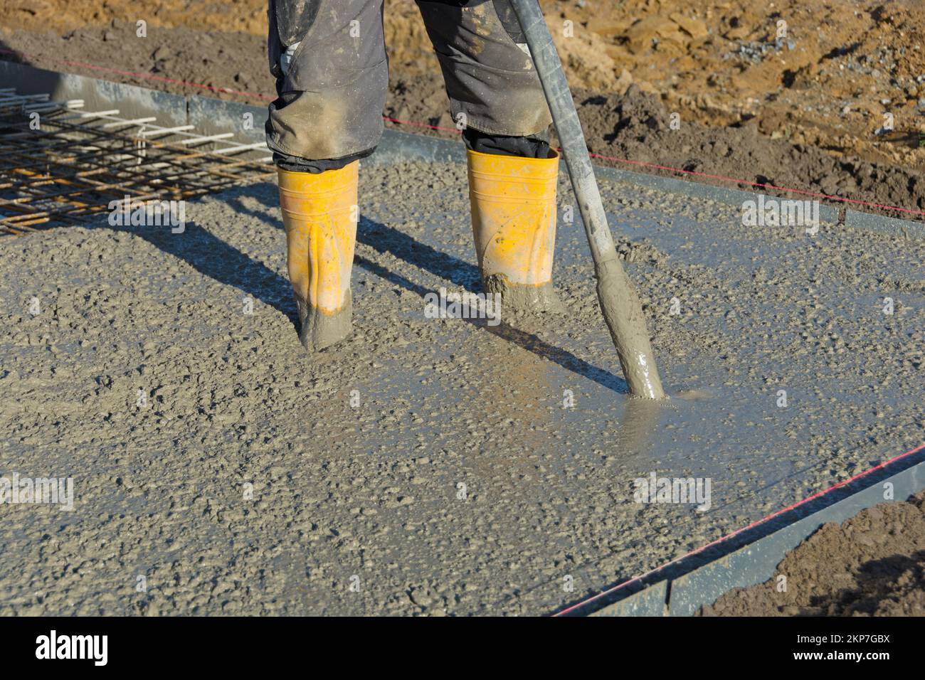 Il calcestruzzo viene compattato dal costruttore con vibratore per calcestruzzo Foto Stock