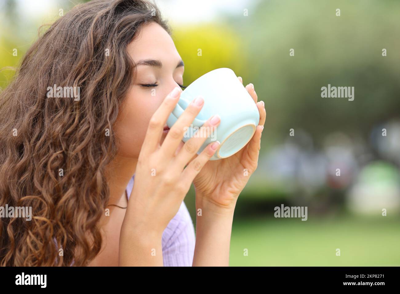 Donna che beve caffè da tazza in un parco Foto Stock