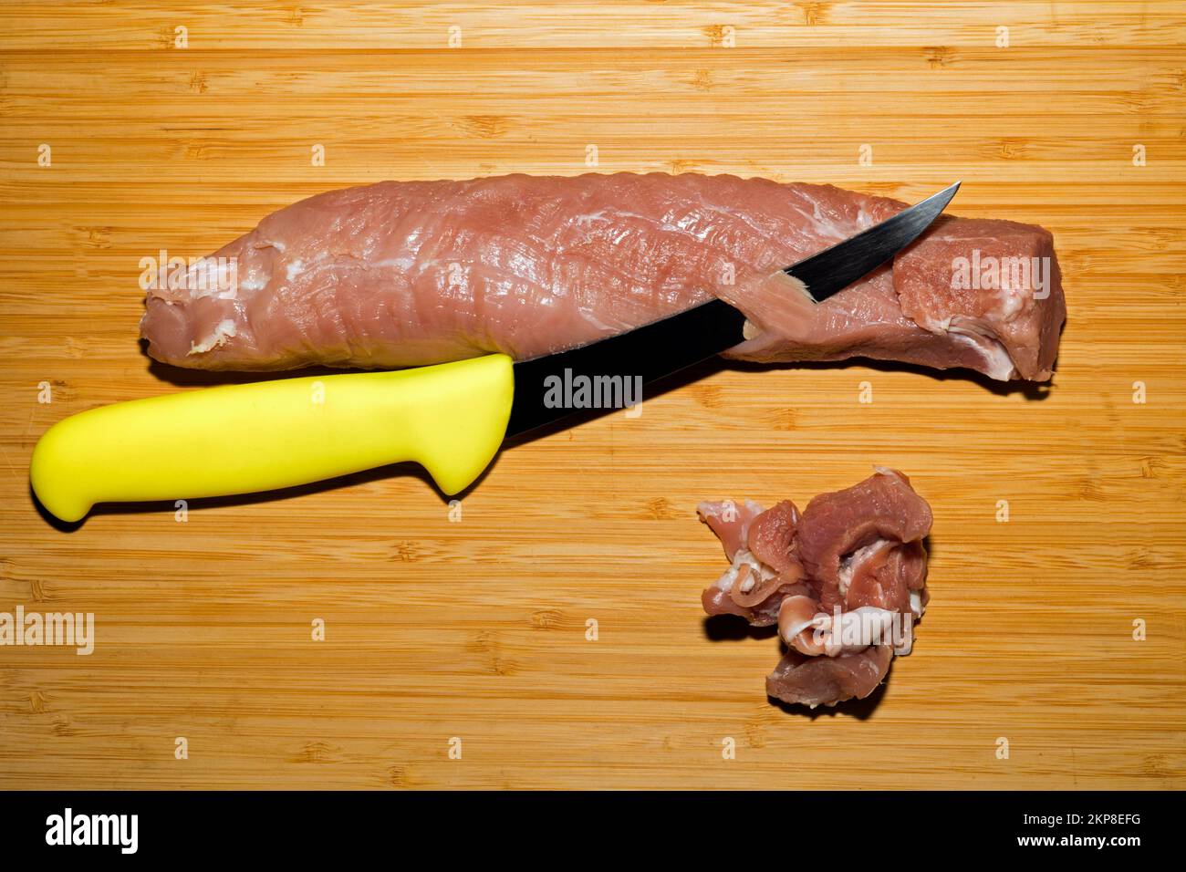 Il filetto di maiale viene liberato dalla pelle d'argento con un coltello, fotografia alimentare Foto Stock