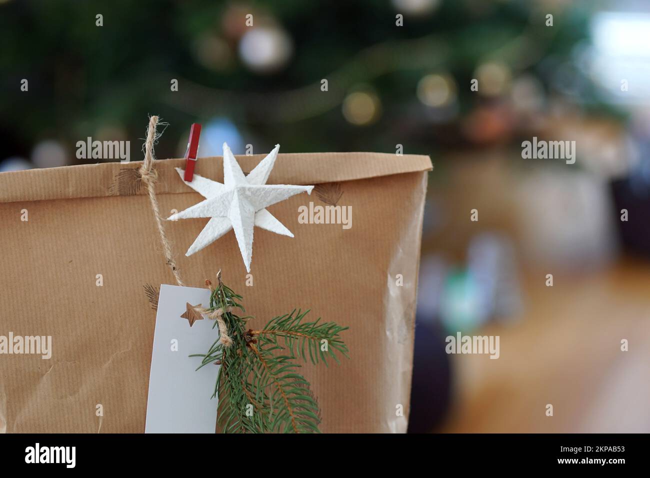Scatola regalo di Natale di carta riciclata con albero di natale in background. Foto Stock