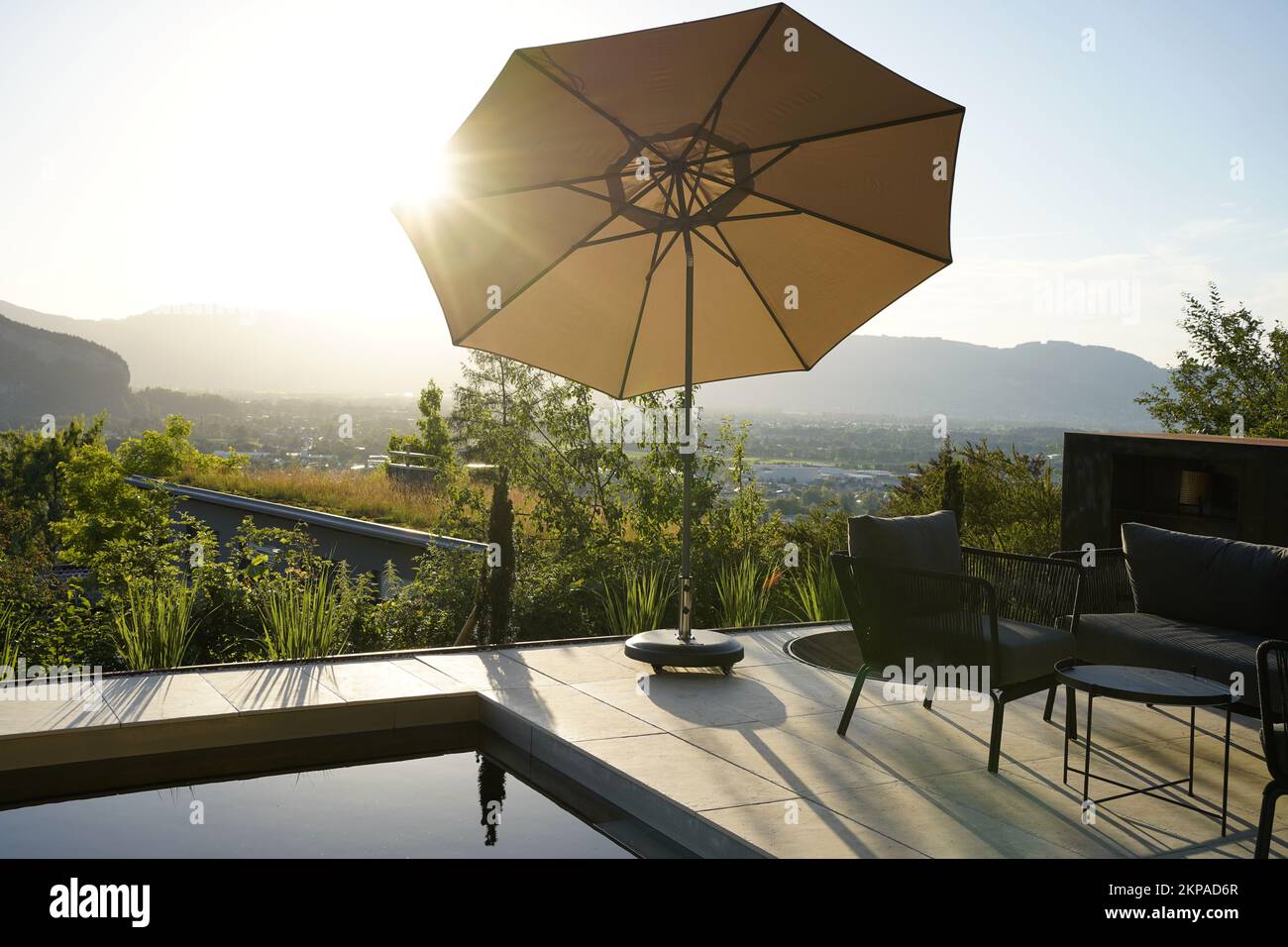 Vista su una terrazza con piscina, ombrellone e mobili da giardino. Foto Stock