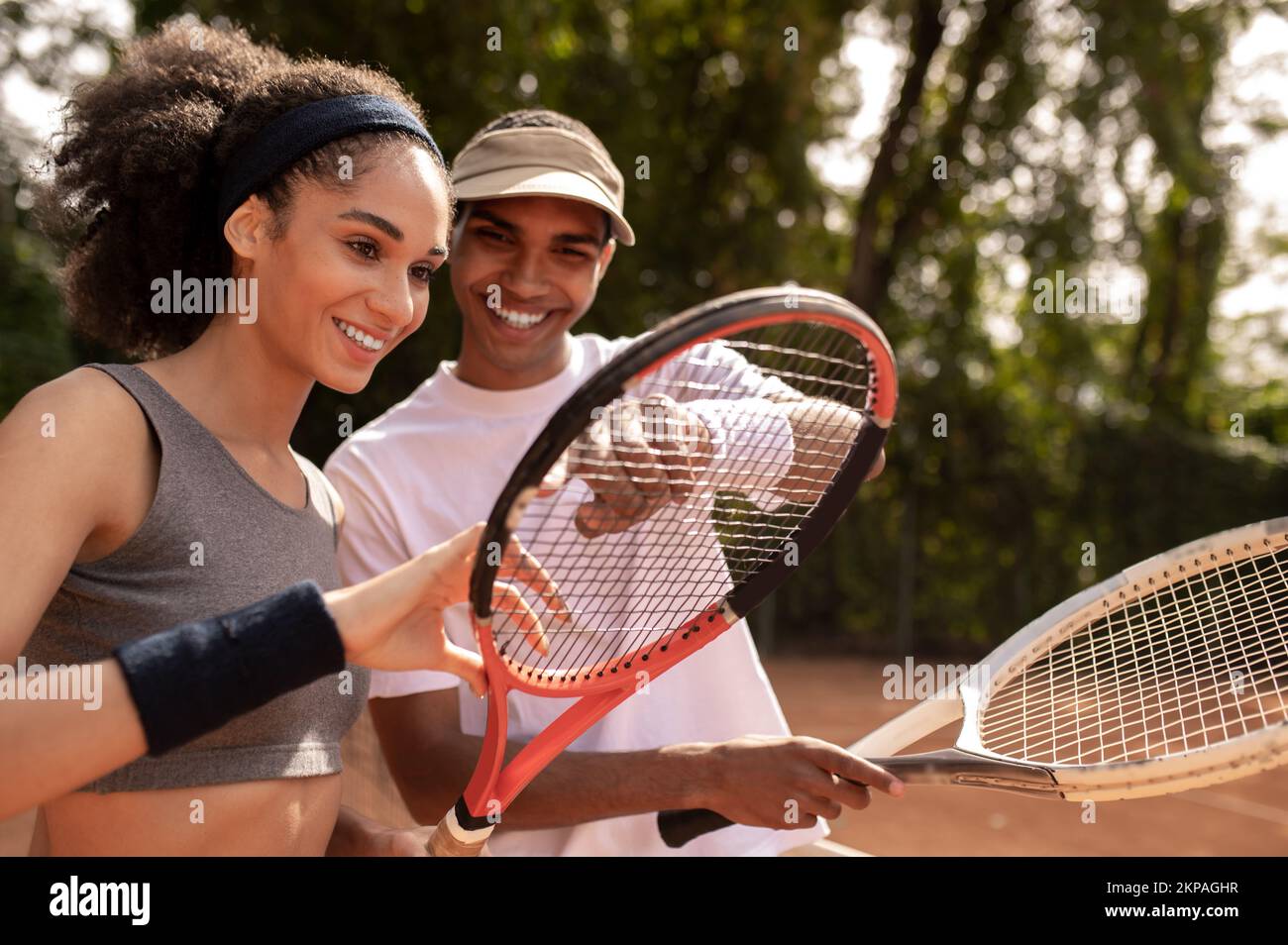 Allenatore maschile che mostra alla ragazza come tenere il racchetta da tennis Foto Stock