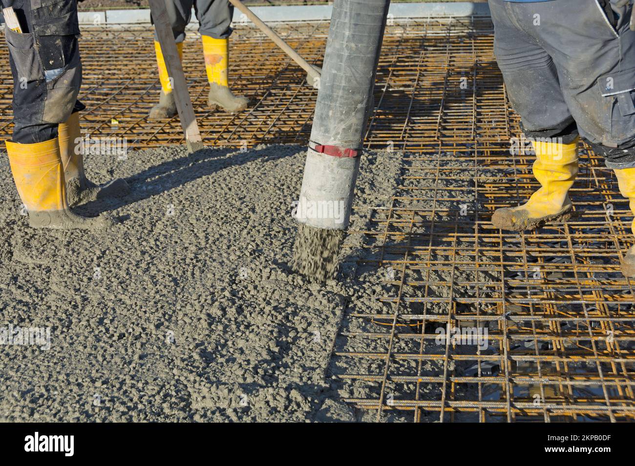 Il lavoratore di costruzione versa calcestruzzo sul tondino usando la pompa di calcestruzzo Foto Stock