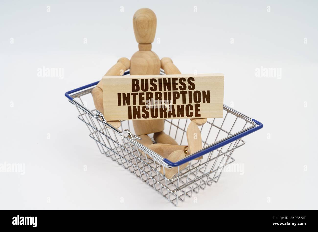 Concetto di business e finanza. Un uomo di legno si siede in un carrello di shopping, tenendo un segno nelle sue mani - assicurazione interruzione di affari Foto Stock