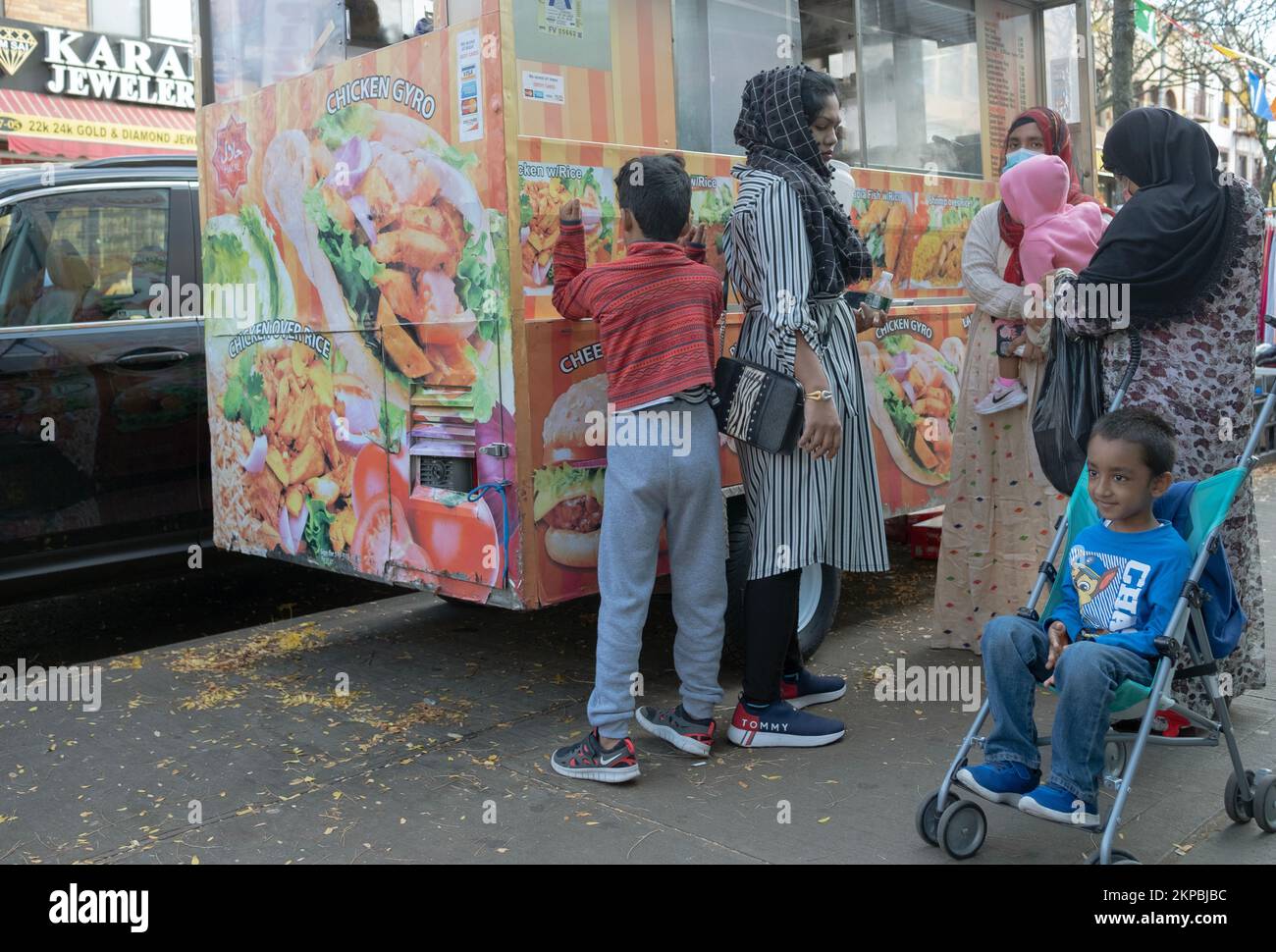 Le donne musulmane in hijab e i loro bambini acquistano cibo in un camion Halal. A Jackson Heights, Queens, New York City. Foto Stock