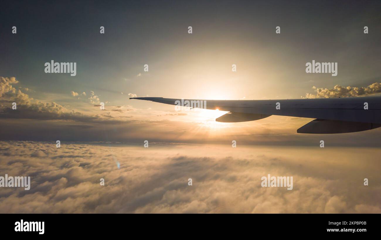 Vista dalla finestra in aereo alle nuvole e al tramonto. Aereo Ala sopra le nuvole sparse Foto Stock