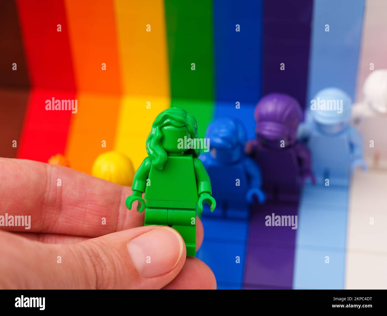Tambov, Federazione Russa - 09 novembre 2022 Una mano donna che tiene una figura verde Lego sopra altre figure iridate. LEGO tutti sono fantastici Foto Stock