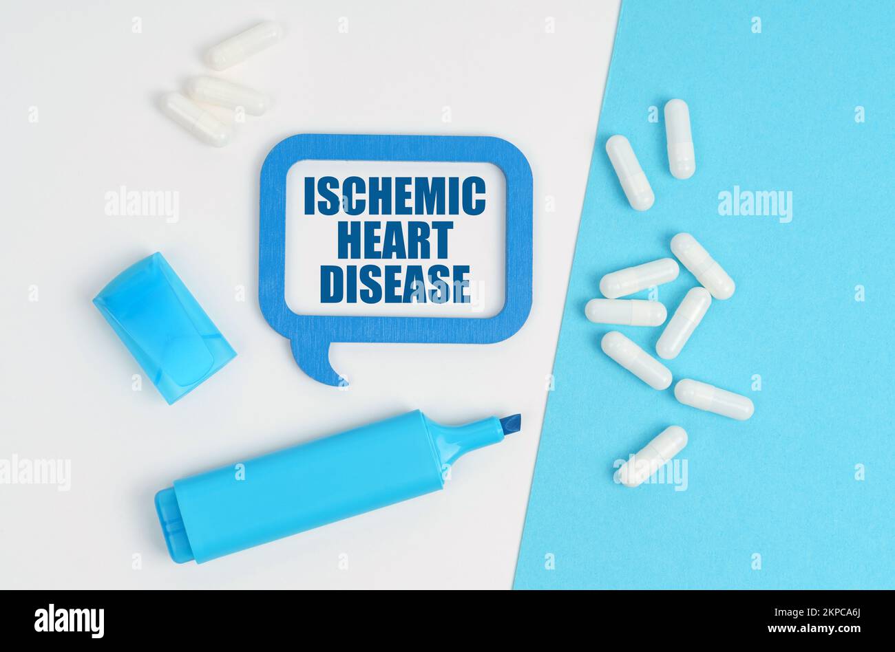 Medicina e concetto di salute. Su una tabella bianca e blu ci sono pillole, un marcatore e una targa blu con l'iscrizione - cardiopatia ischemica Foto Stock
