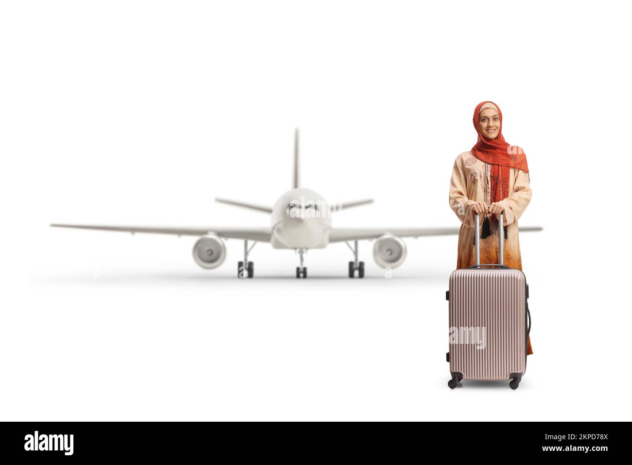 Giovane donna in abiti etnici e hijab con una valigia posta di fronte ad un aereo isolato su sfondo bianco Foto Stock