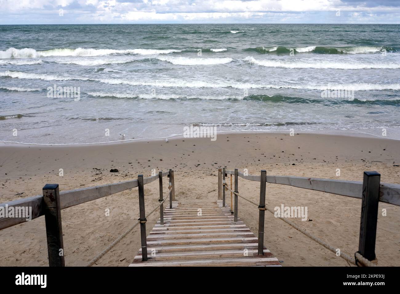 Paesaggio con spiaggia di sabbia vuota, mare e lunghe scale che vanno verso la costa Foto Stock