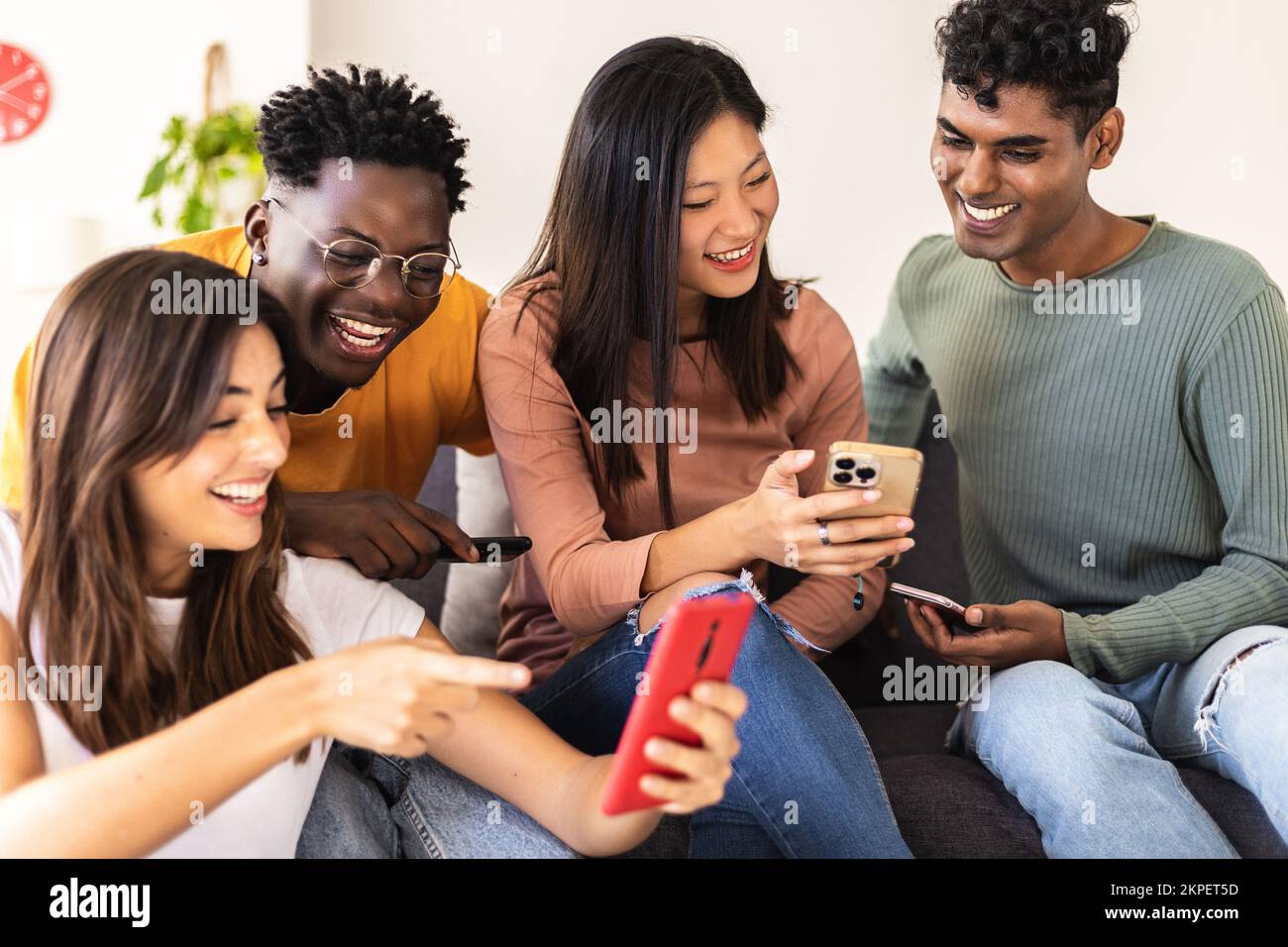 Gruppo di giovani diversi che si divertono a usare lo smartphone a casa Foto Stock