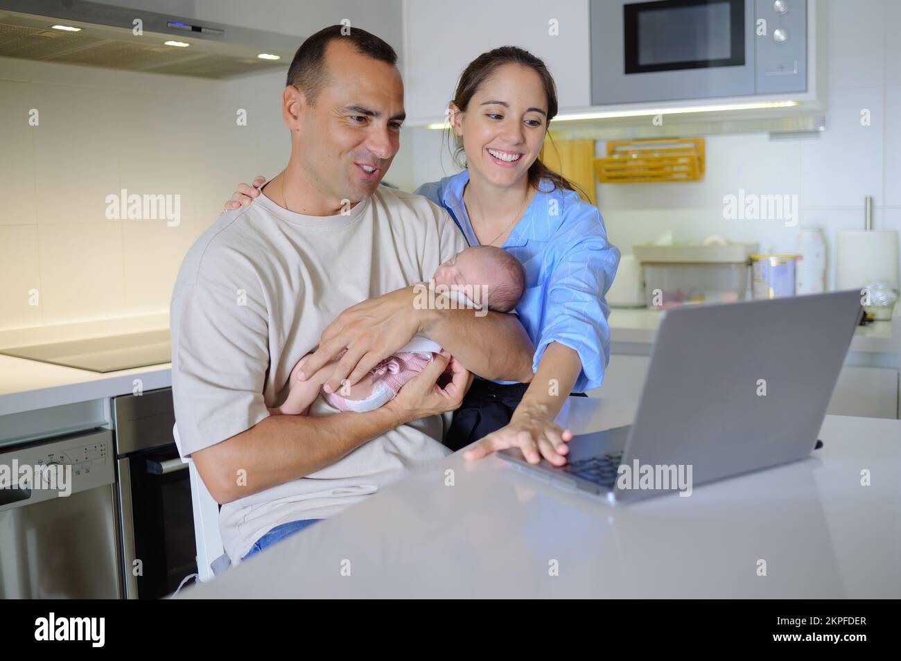 Famiglia felice con il bambino che utilizza netbook in cucina moderna Foto Stock