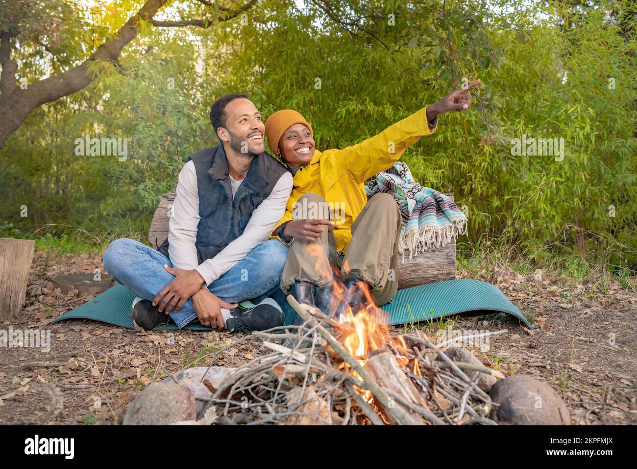 Coppia multietnica seduta fuori intorno al fuoco del campo. Godersi la natura vita sana Foto Stock